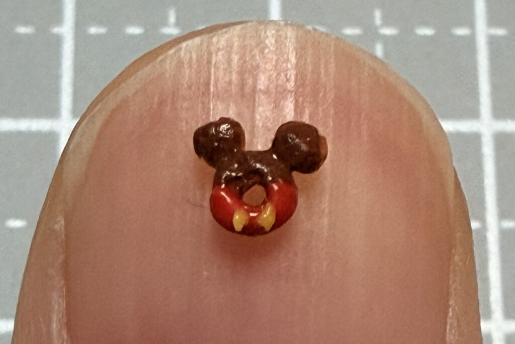 ミニチュアのドーナツを爪にのせている